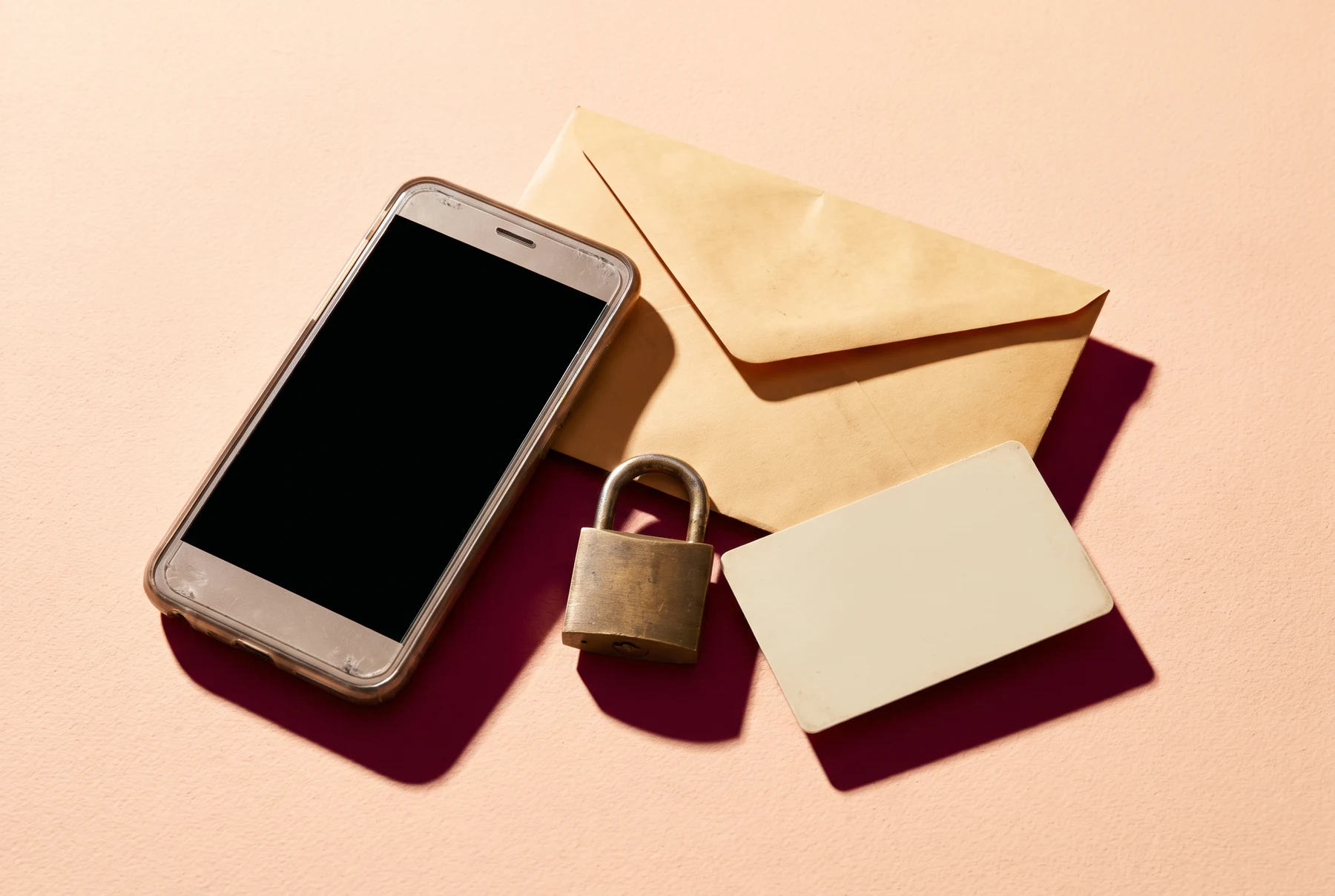 Phone, envelope and lock arranged on a peach desk